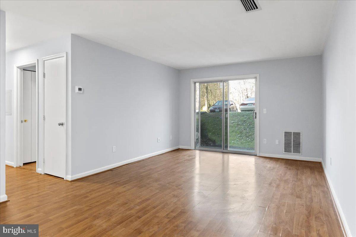 an empty room with wooden floor and windows