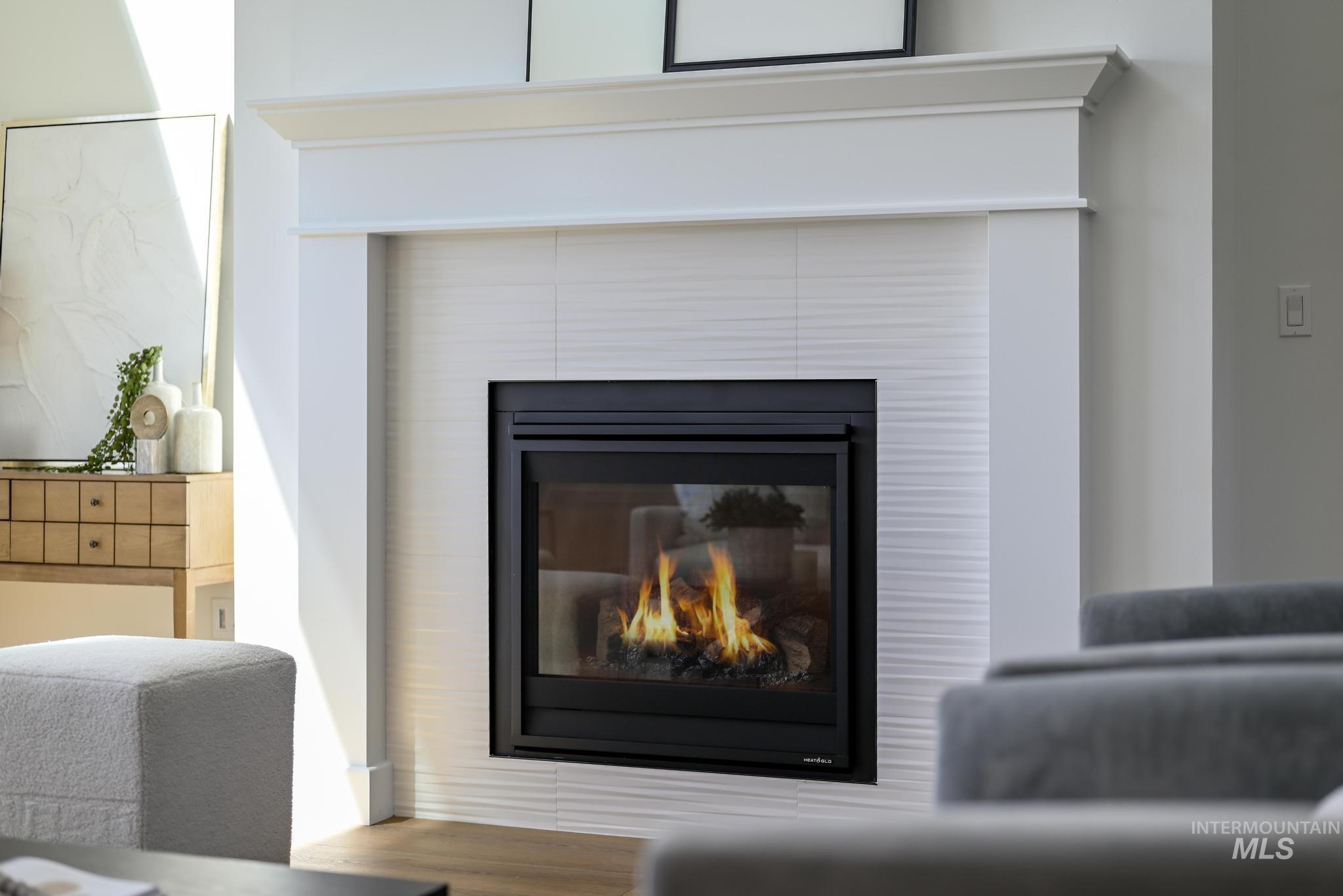 14703 Serenity Pt Street Caldwell, ID 83607 - Photo 7 of 45 Built-in fireplace with a black glass front, white textured tile surround, and a classic white mantelpiece
