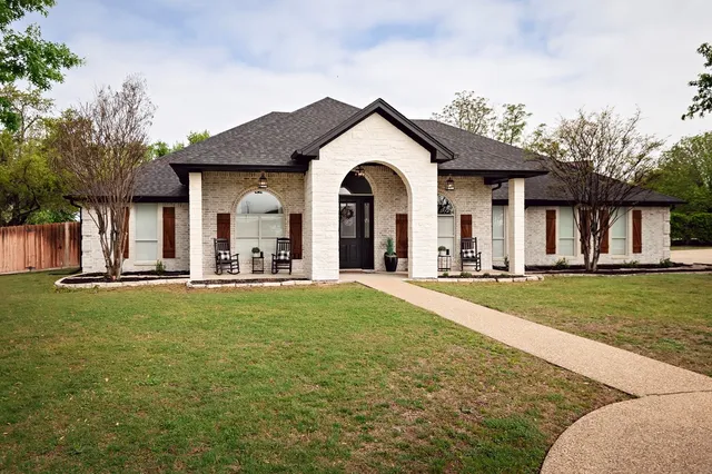 a view of a house with a big yard and large trees