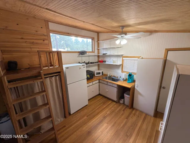 a kitchen with sink a refrigerator a window and wooden floor