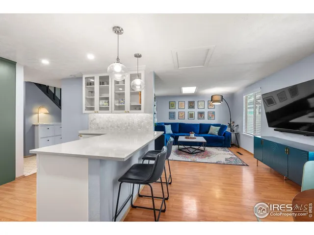 a kitchen with stainless steel appliances granite countertop a stove top oven a sink dishwasher a dining table and chairs with wooden floor