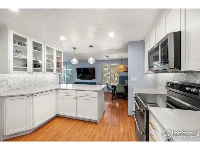 a kitchen view with stainless steel appliances kitchen island granite countertop a refrigerator stove oven a sink dishwasher and white cabinets with wooden floor