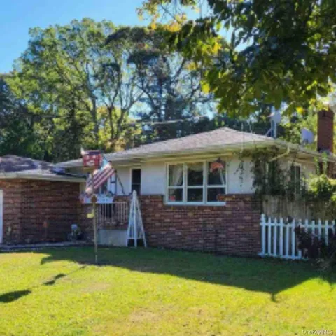 a view of a house with a yard potted plants and large tree