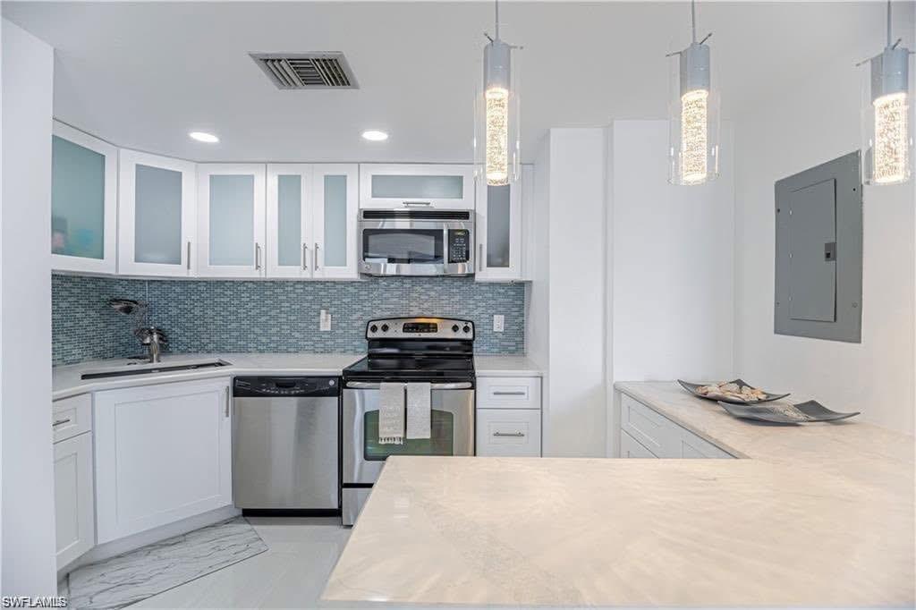 58 North Collier Boulevard, Unit 1010 Marco Island, FL 34145 - Photo 4 of 12 a kitchen with stainless steel appliances granite countertop a stove top oven a sink a refrigerator white cabinets and wooden floor