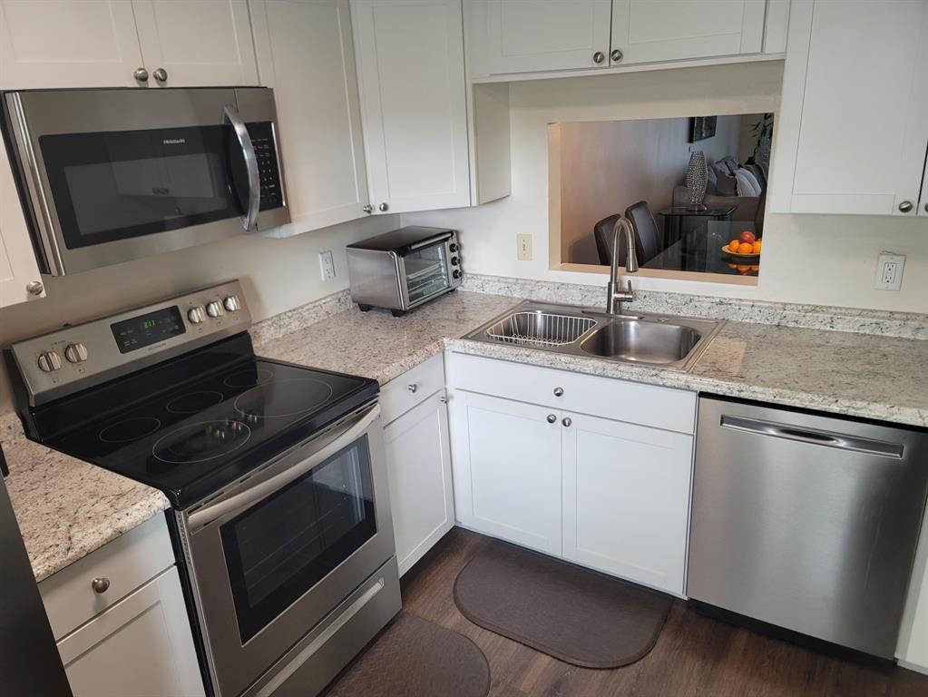 3774 Inverrary Boulevard, Unit P202 Lauderhill, FL 33319 - Photo 6 of 31 a kitchen with granite countertop a sink dishwasher stove and microwave with wooden floor