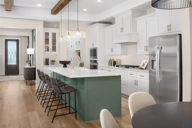 a kitchen with stainless steel appliances kitchen island granite countertop a dining table chairs and a refrigerator