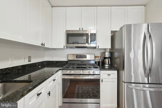 a kitchen with granite countertop a sink stove and refrigerator