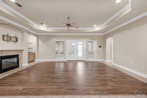 a view of an empty room with wooden floor fireplace and a window