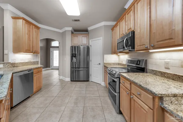 a kitchen with stainless steel appliances granite countertop a stove top oven a sink and a refrigerator
