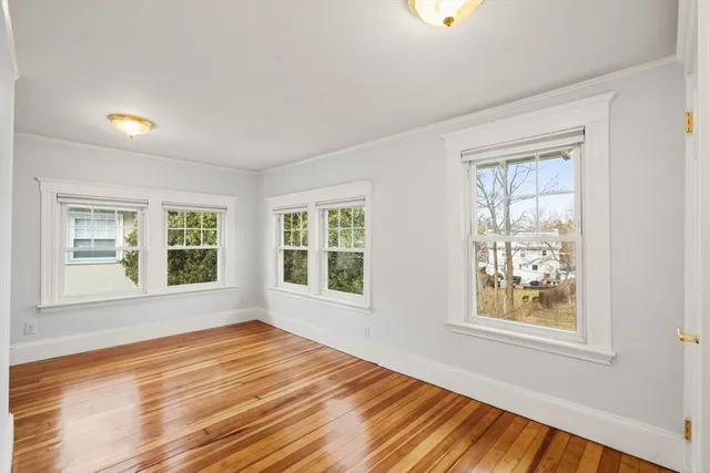a view of an empty room with a window and wooden floor