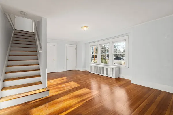 a view of an empty room with wooden floor and windows