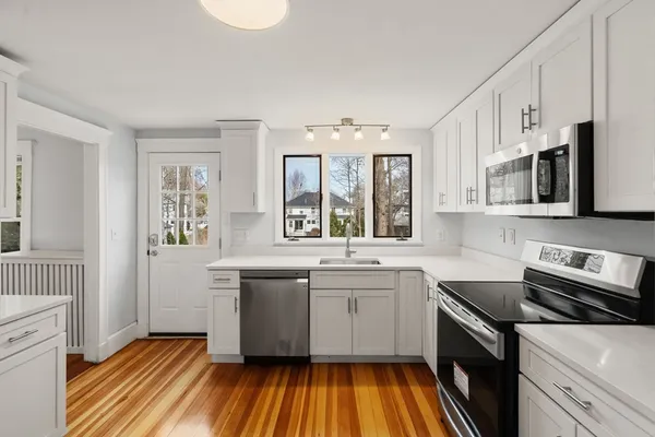 a kitchen with stainless steel appliances a sink cabinets and wooden floor