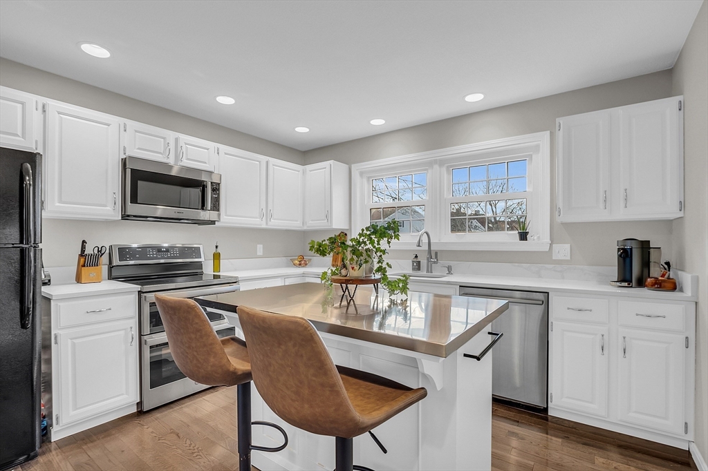 2 Countryside Lane, Unit 1301 Salem, MA 01970 - Photo 2 of 37 a kitchen with granite countertop a stove a sink a microwave a dining table and chairs