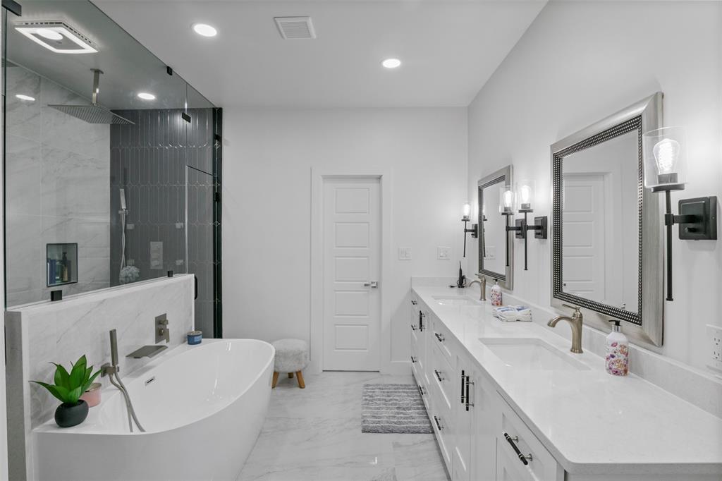 200 Corral Road Godley, TX 76044 - Photo 13 of 19 a bathroom with a double vanity sink a large mirror and a bathtub