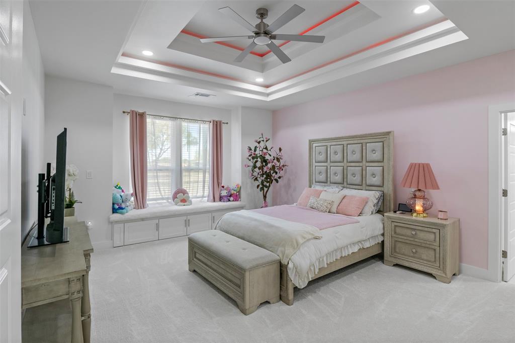 200 Corral Road Godley, TX 76044 - Photo 10 of 19 a spacious bedroom with a bed a couch and a chandelier