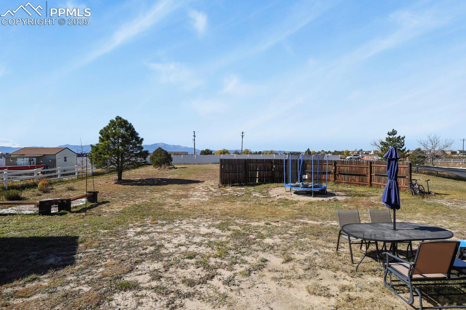 7660 Bullet Road Peyton, CO 80831 - Photo 38 of 50 Fenced backyard featuring a trampoline, a mountain view, and a patio