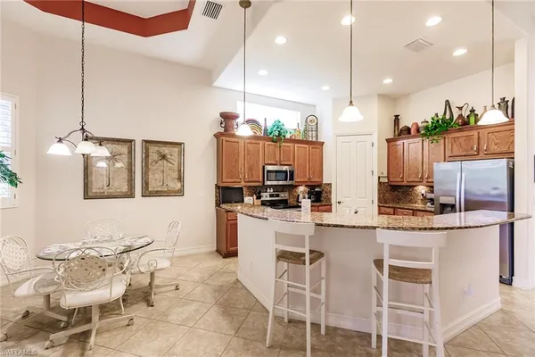 a kitchen with stainless steel appliances kitchen island granite countertop a table chairs and a refrigerator