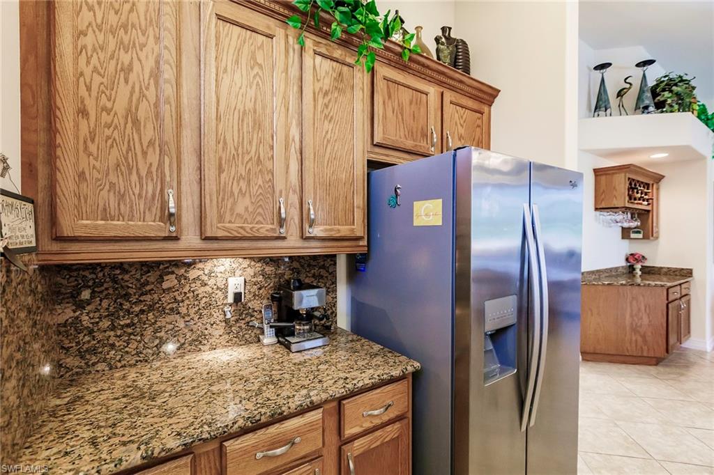 7684 Cottesmore Drive Naples, FL 34113 - Photo 19 of 46 a kitchen with granite countertop a refrigerator and a stove