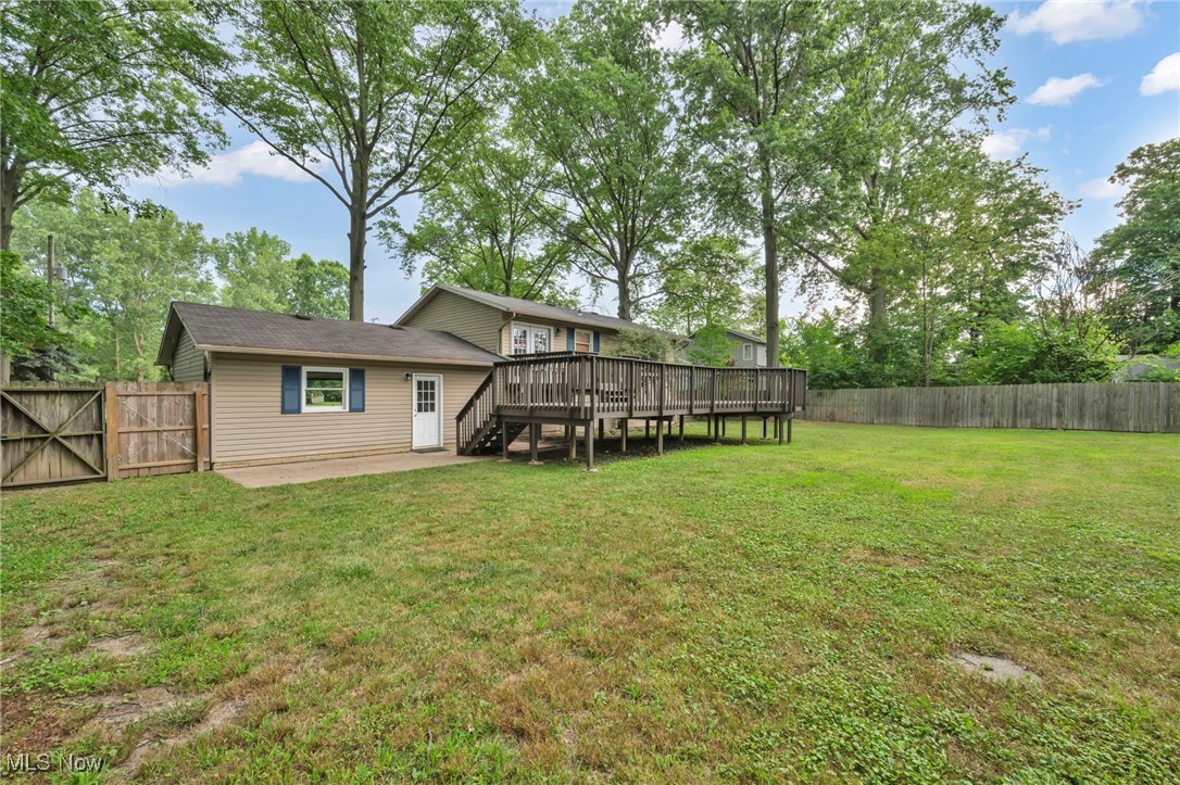 47655 Cooper Foster Park Road Amherst, OH 44001 - Photo 42 of 49 Rear view of property featuring a wooden deck, a fenced backyard, a gate, and view of scattered trees