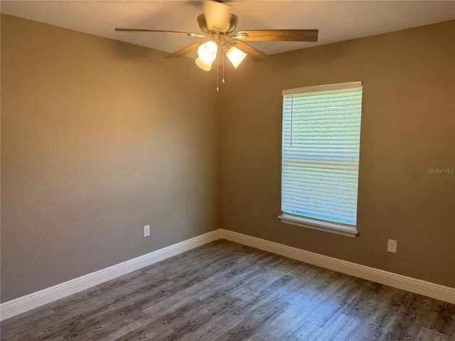 an empty room with a window and wooden floor