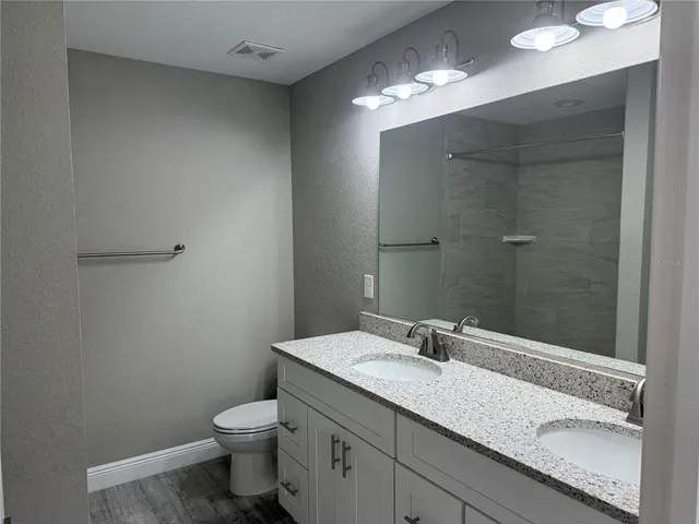a bathroom with a granite countertop sink a toilet and a mirror