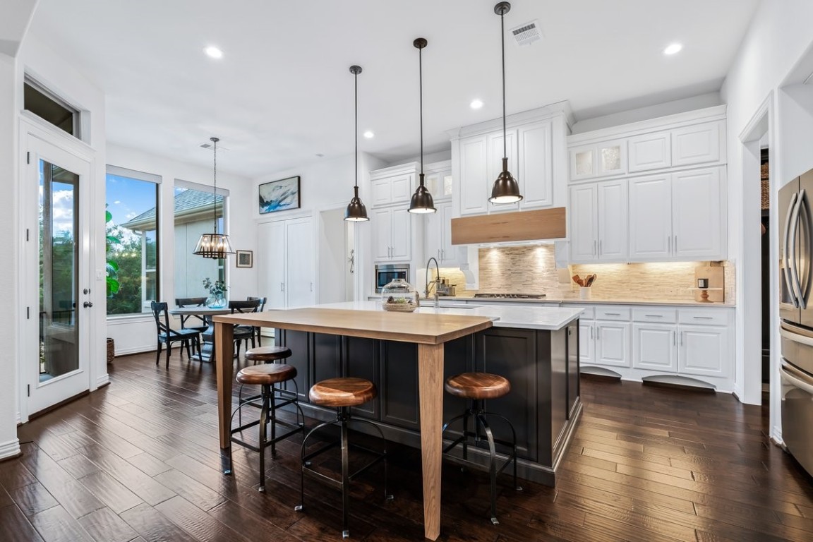 a kitchen with stainless steel appliances granite countertop a kitchen island a stove a table and chairs