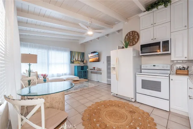 a kitchen with stainless steel appliances granite countertop a stove a microwave a sink a dining table and chairs with white cabinets