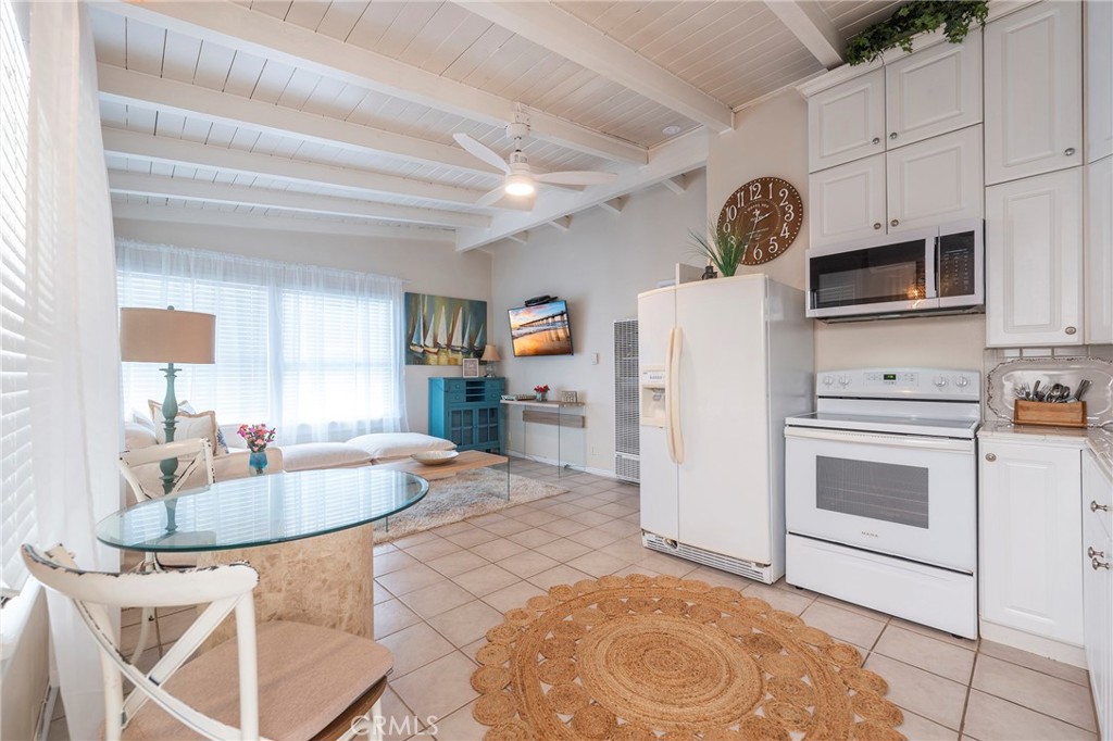 1728 The Strand, Unit 4 Hermosa Beach, CA 90254 - Photo 8 of 23 a kitchen with stainless steel appliances granite countertop a stove a microwave a sink a dining table and chairs with white cabinets