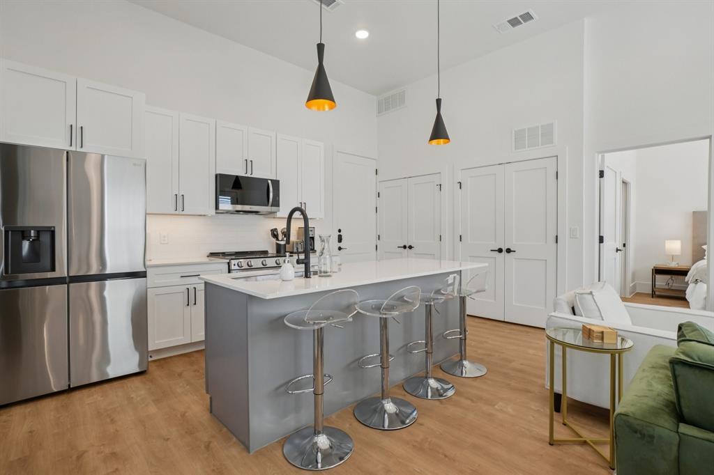 6418 Maple Avenue, Unit 302 Dallas, TX 75235 - Photo 2 of 16 a kitchen with stainless steel appliances granite countertop a stove a sink a refrigerator and white cabinets with wooden floor