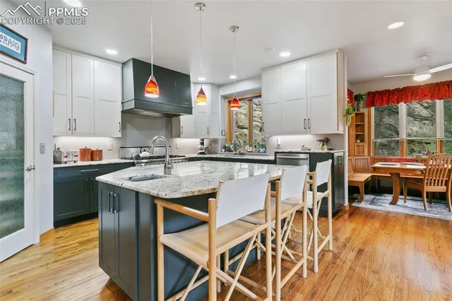 a kitchen with stainless steel appliances kitchen island granite countertop a table chairs in it and wooden floors