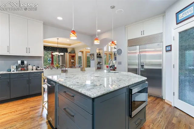 a kitchen with stainless steel appliances granite countertop a sink a counter space and wooden floor