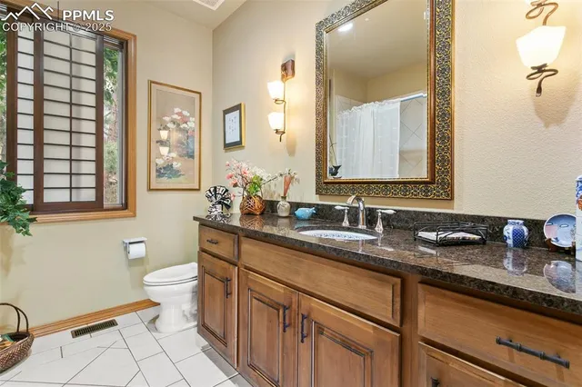 a bathroom with a granite countertop sink a toilet a mirror and a shower