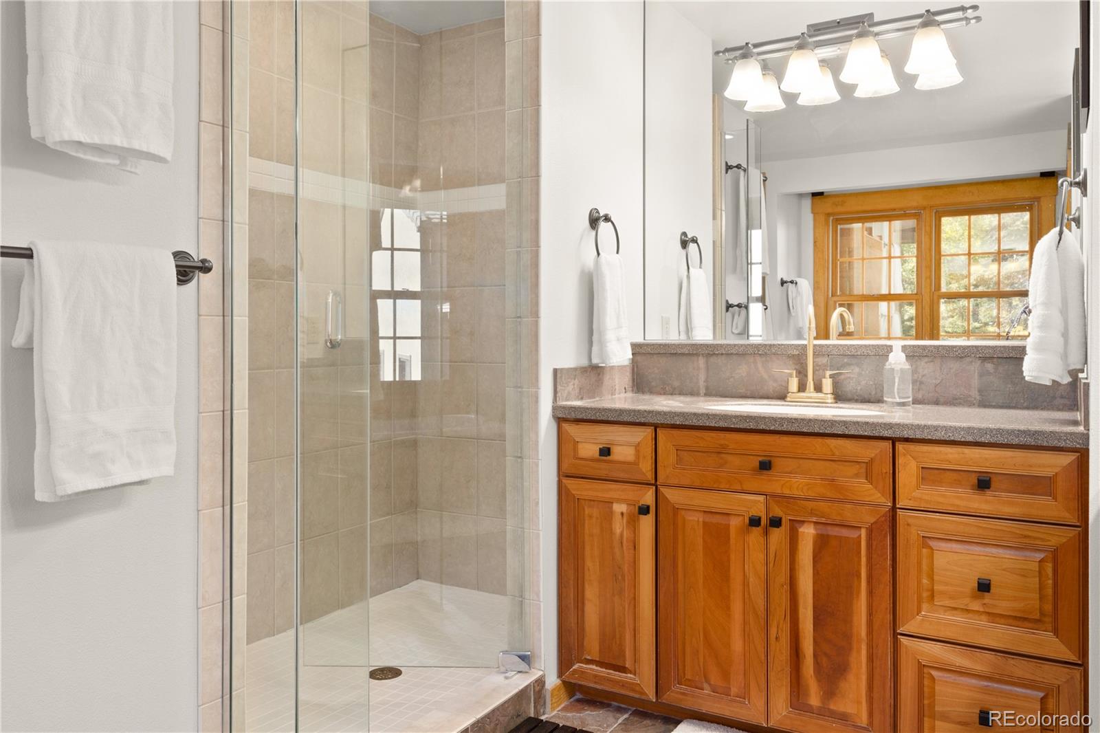 32217 Buffalo Park Road Evergreen, CO 80439 - Photo 14 of 46 a bathroom with a shower sink and mirror