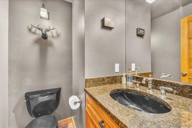 a bathroom with a granite countertop sink toilet and mirror