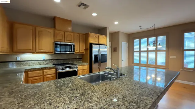 a kitchen with stainless steel appliances granite countertop a stove a sink and a microwave