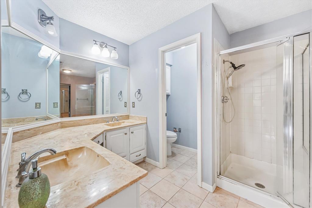 1301 Memory Lane, Unit 4924 Arlington, TX 76011 - Photo 13 of 19 Bathroom featuring a shower stall, double vanity, a textured ceiling, and light tile patterned floors