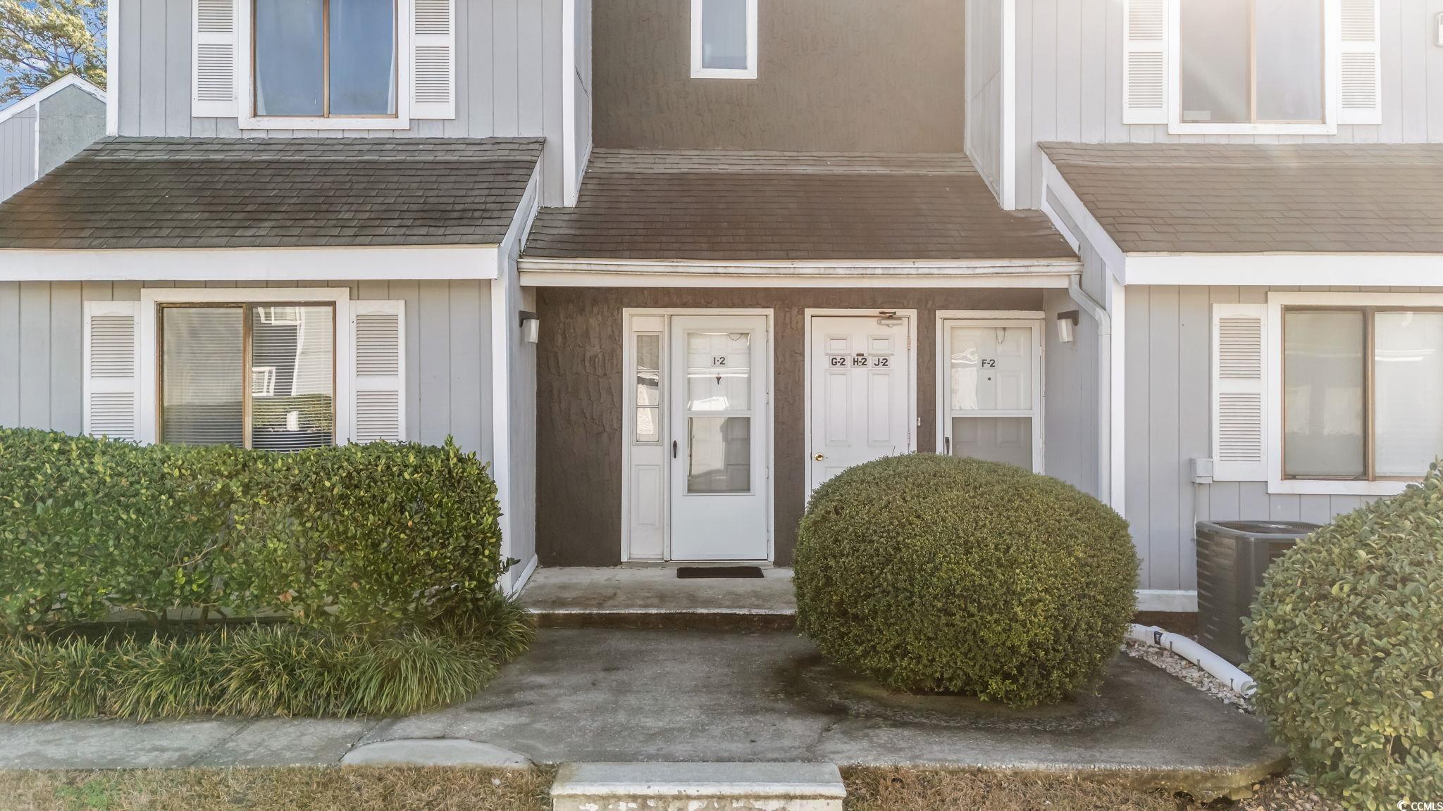 Doorway to property with board and batten siding and a shingled roof