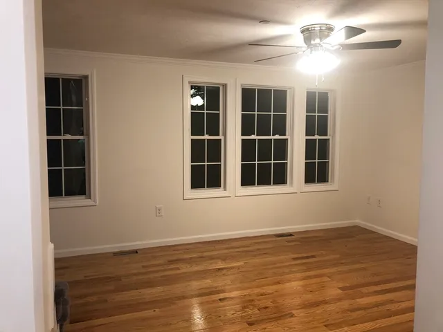 a view of an empty room with a window and wooden floor