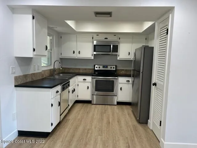 a kitchen with stainless steel appliances a stove a sink a refrigerator a microwave and cabinets