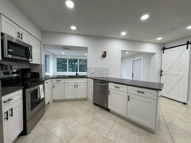 1632 Northwest 5th Street Boca Raton, FL 33486 - Photo 6 of 22 a large white kitchen with stainless steel appliances granite countertop white cabinets a sink a stove a microwave and a refrigerator