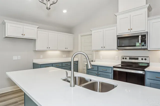 a kitchen with white cabinets a sink and stainless steel appliances