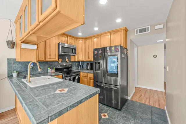 a kitchen with stainless steel appliances granite countertop a refrigerator a sink a stove a microwave and island