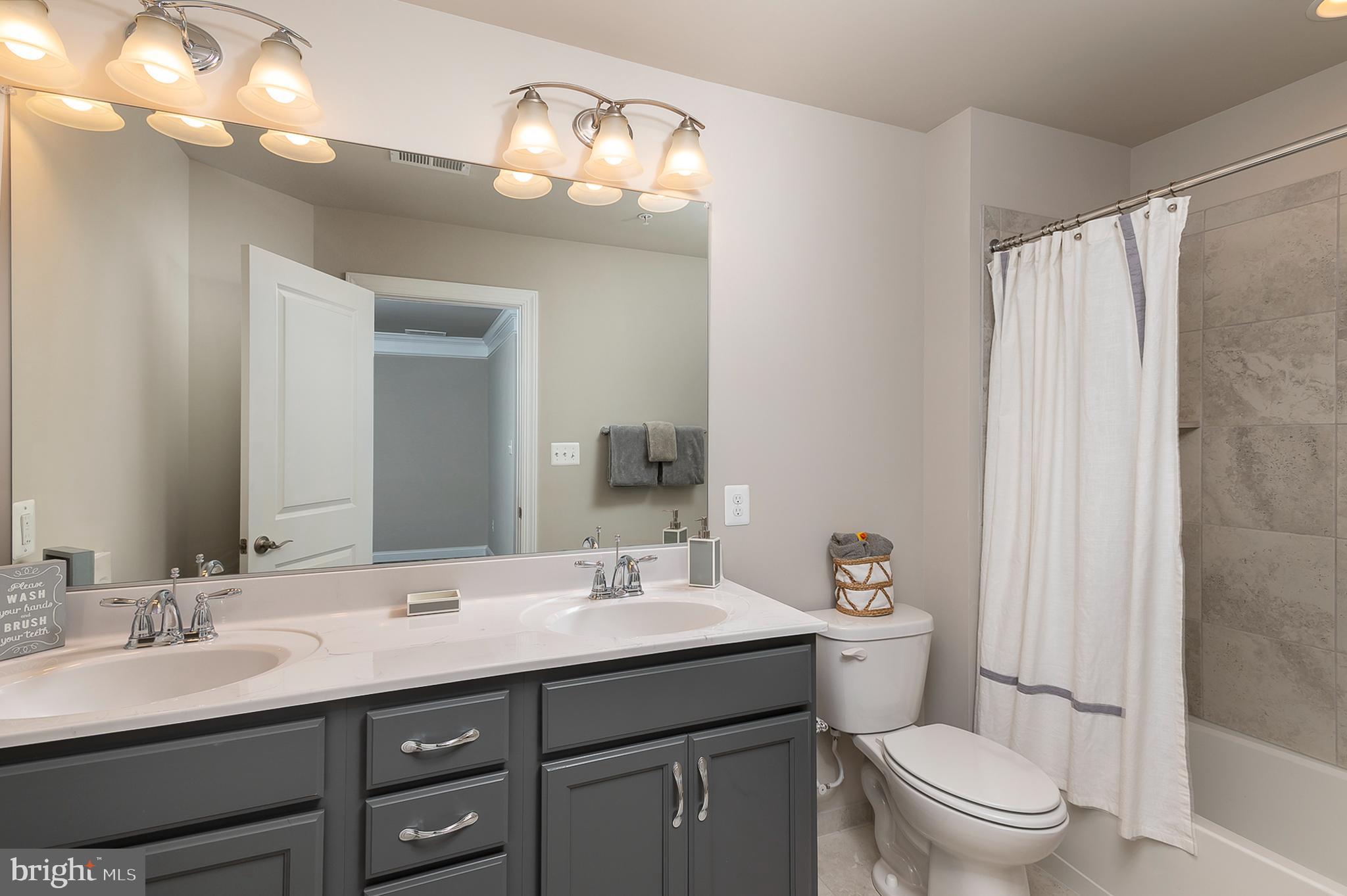 4468 Ilchester Road Ellicott City, MD 21043 - Photo 7 of 32 a bathroom with a double vanity sink toilet and a mirror