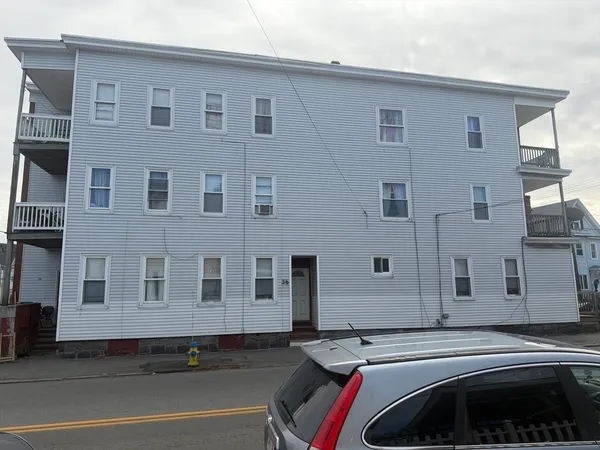 a front view of a house with a car parked on road