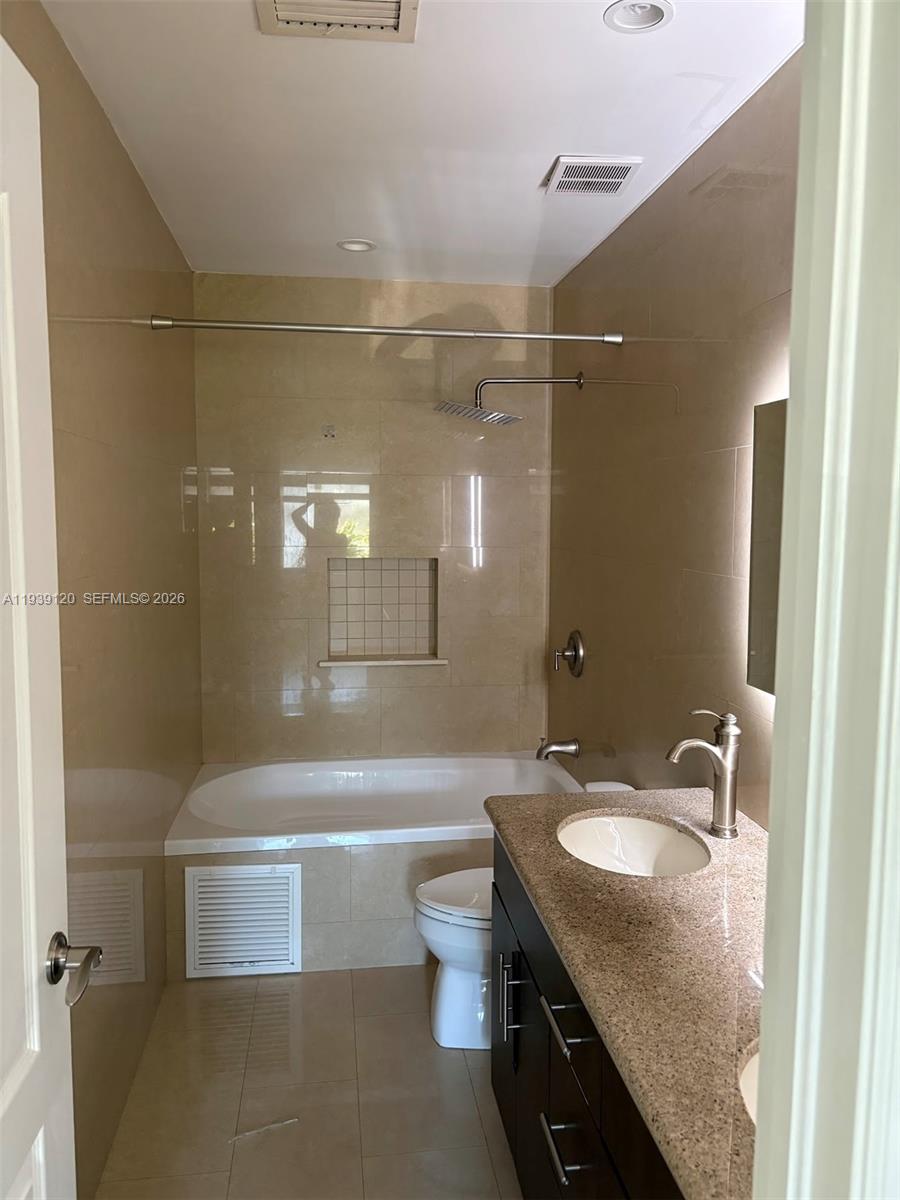5555 Ludlam Road, Unit 105 South Miami, FL 33155 - Photo 22 of 29 a bathroom with a granite countertop sink a toilet a mirror and bathtub
