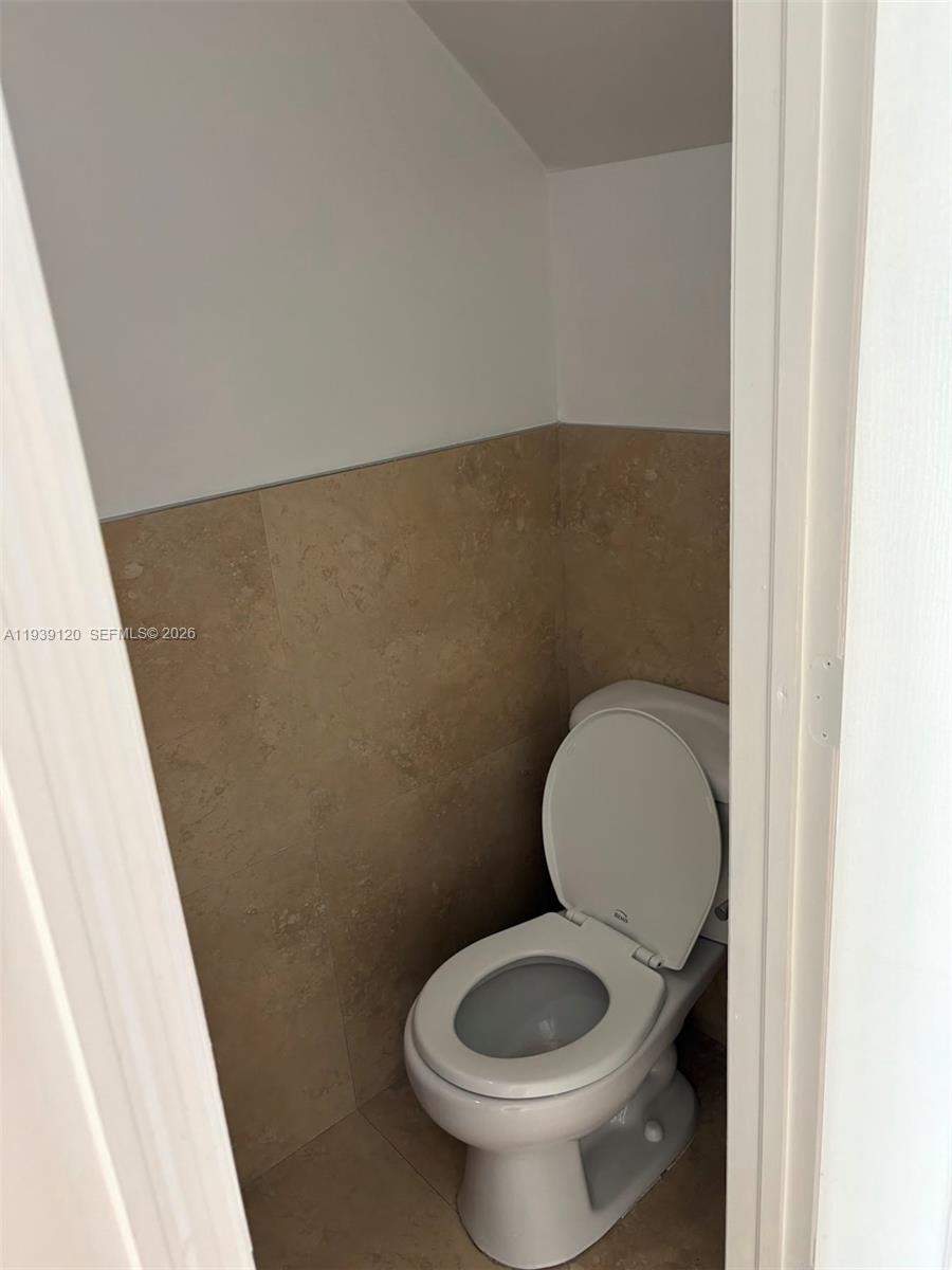 5555 Ludlam Road, Unit 105 South Miami, FL 33155 - Photo 26 of 29 a toilet sitting in a bathroom next to a wooden wall
