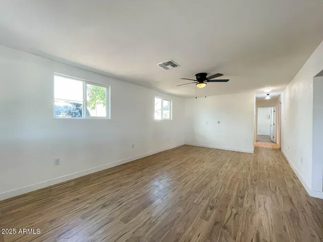 an empty room with wooden floor and windows