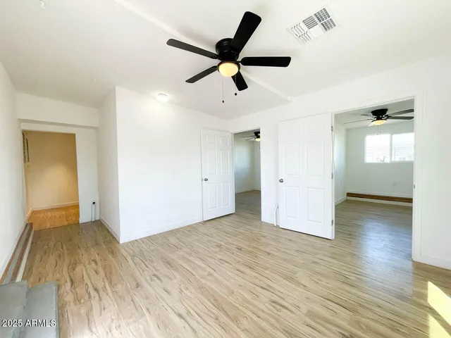a view of empty room with wooden floor and ceiling fan