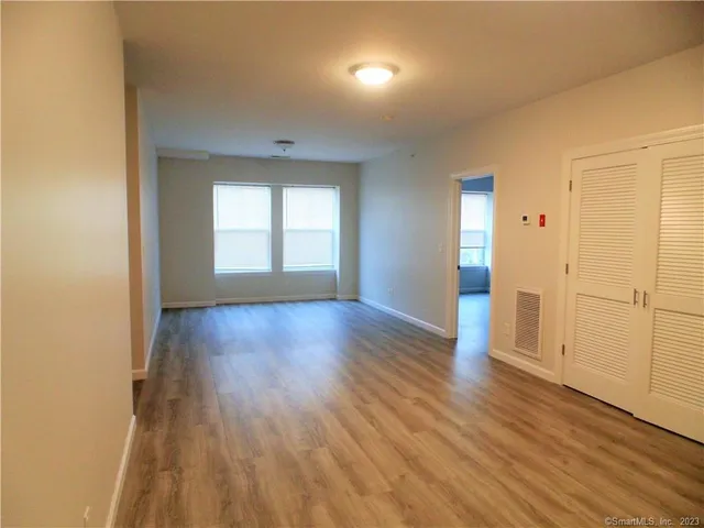 an empty room with wooden floor and windows