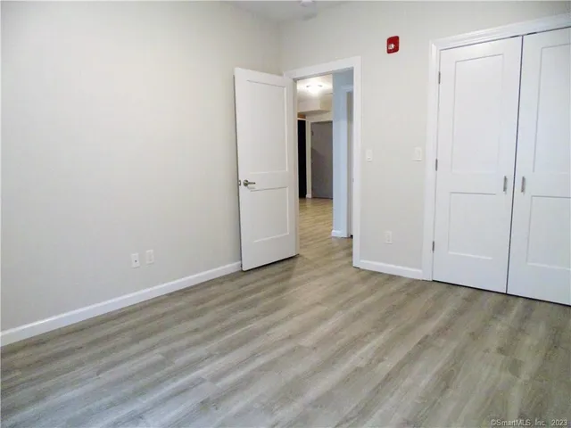 a view of an empty room with closet and wooden floor